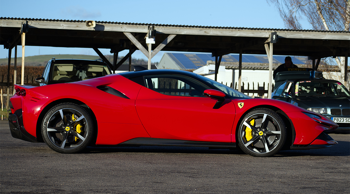 Une Ferrari rouge vue de côté devant un parking couvert